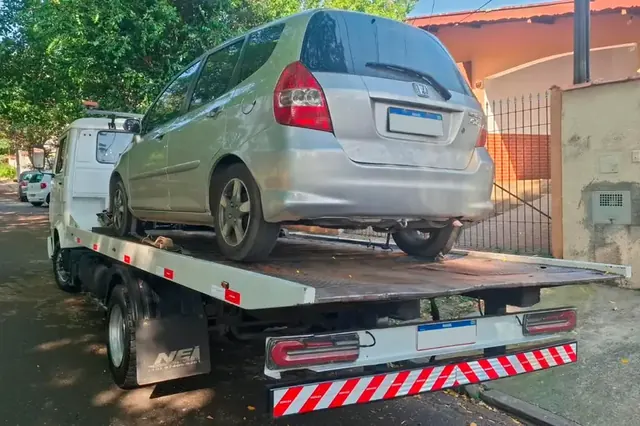 Carro prata rebocado no guincho plataforma durante um atendimento